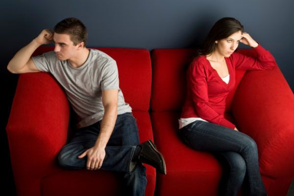 man and woman angrily looking away from each other on red couch